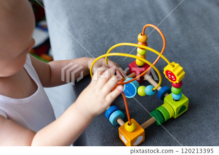 Closeup: little child learning about orders, sorting, arranging by engaged colourful wooden sensorial parts. Educational toys, Cognitive skills, Montessori activity. Selective focus. Closeup: little child learning about orders, sorting, arranging by engaged colourful wooden sensorial parts. Educational toys, Cognitive skills, Montessori activity. Selective focus. 120213395