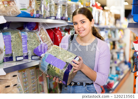 Young woman picking out packed hay in pet shop 120213501