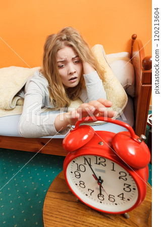 Woman waking up turning off alarm clock in morning Woman waking up turning off alarm clock in morning 120213604