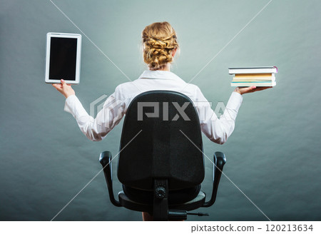 Woman holding traditional book and e-book reader 120213634