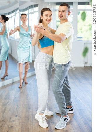 Couple in comfortable sports clothes waltz dancing during individual lesson 120213728