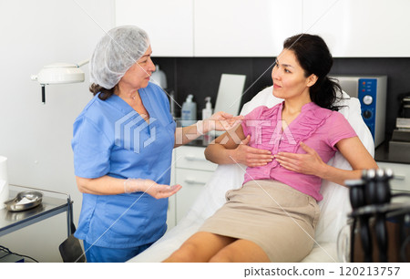 Woman asking cosmetologist about breast lift and reshaping procedures 120213757