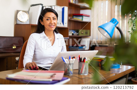 Latin american businesswoman sitting in office at workplace 120213792