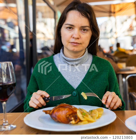 Female tourist tasting Toston asado in restaurant of Salamanca 120213803
