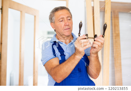 Professional door installer checks operation of bronze door handles Professional door installer checks operation of bronze door handles 120213855