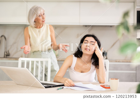 Elderly woman quarrels with young woman working at laptop 120213953
