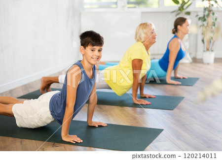 Mother, grandmother and teen son do exercise upward facing dog pose, Urdhva Mukha Svanasana pose 120214011
