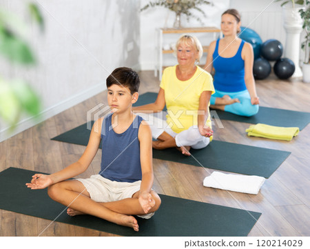 Group of people generation on mats doing yoga exercise lord of fishes pose. 120214029