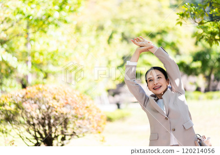 一個穿著西裝的女人坐在公園的長椅上伸展身體 一個穿著西裝的女人坐在公園的長椅上伸展身體 120214056