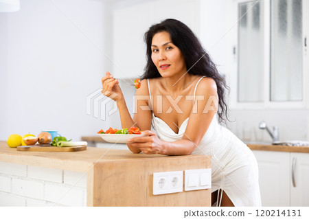 Portrait of woman eating salad at home Portrait of woman eating salad at home 120214131