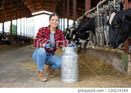 Positive young woman farmer squatting at milk can Positive young woman farmer squatting at milk can 120214169
