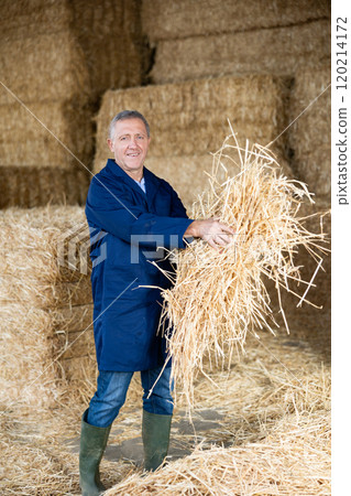 Portrait of male farmer with a straw in her hands in an animal feed warehouse 120214172