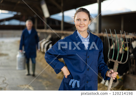 Experienced female farmer standing with pitchfork in livestock farm Experienced female farmer standing with pitchfork in livestock farm 120214198