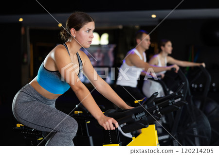 Girl performs exercises with stationary bicycle in gym 120214205