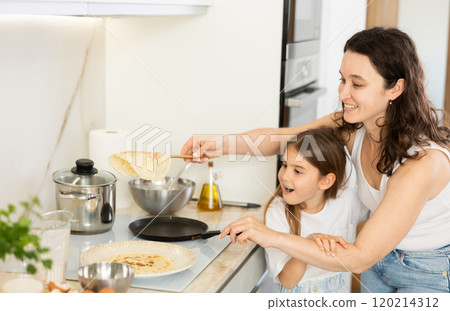 Mom and her daughter fry pancakes Mom and her daughter fry pancakes 120214312