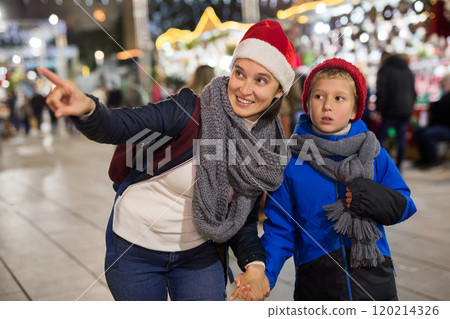 Happy tween boy and his mom walking at street Christmas fair Happy tween boy and his mom walking at street Christmas fair 120214326