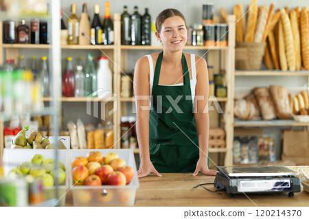 Young woman seller at counter in grocery store 120214370