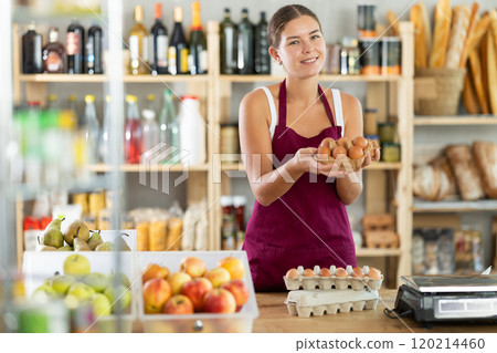 Young woman seller offering eggs in grocery store 120214460