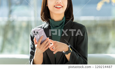 A young woman/businesswoman using a smartphone with a smile 120214487