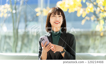 A young woman/businesswoman using a smartphone with a smile 120214488
