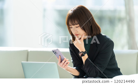 A woman/businesswoman thinking seriously while using a computer and smartphone 120214490