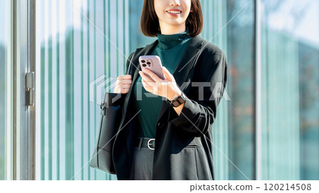 Young woman/businesswoman holding a smartphone outdoors 120214508