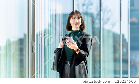 Young woman/businesswoman holding a smartphone outdoors 120214509