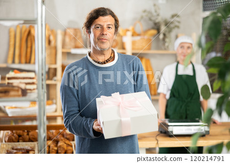Positive man bought cake in bakery, packed in white elegant box with pink bow Positive man bought cake in bakery, packed in white elegant box with pink bow 120214791