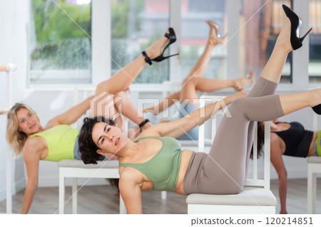Group of women in high heels rehearsing dance while lying on chair Group of women in high heels rehearsing dance while lying on chair 120214851