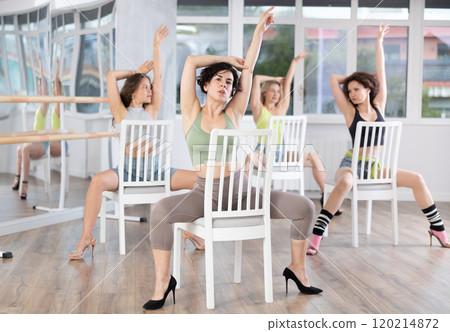 Group of women in high heels rehearsing dance while sitting on chair 120214872