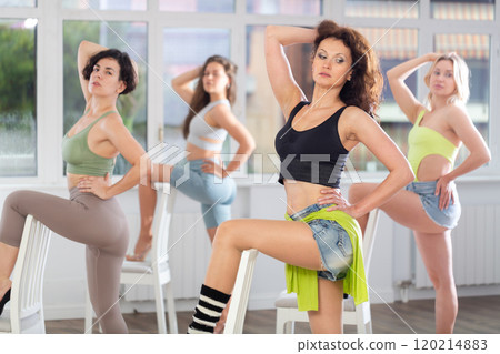Group of women in high heels rehearsing dance with their feet on chair 120214883