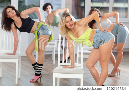 Putting foot hand on seat of chair, girl improvises, perform lap dance during group master class 120214884