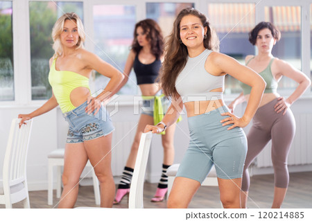 Group of girls unleash their energy and dance passionately near a chair in high heels in a dance studio. His powerful moves combined with elegance of high heels Group of girls unleash their energy and dance passionately near a chair in high heels in a dance studio. His powerful moves combined with elegance of high heels 120214885
