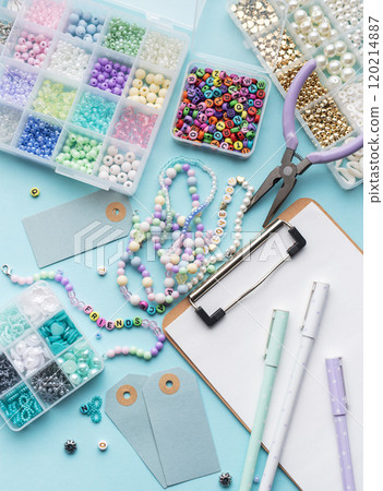 Colorful beads, pliers, clipboard and price tags arranged on blue surface for diy bracelet making Colorful beads, pliers, clipboard and price tags arranged on blue surface for diy bracelet making 120214887
