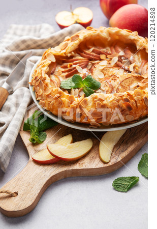 Delicious homemade apple galette with almond flakes and fresh mint on rustic background 120214898