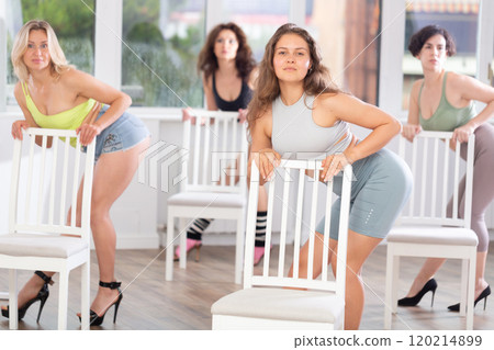 Group of girls unleash their energy and dance passionately near a chair in high heels in a dance studio. His powerful moves combined with elegance of high heels Group of girls unleash their energy and dance passionately near a chair in high heels in a dance studio. His powerful moves combined with elegance of high heels 120214899