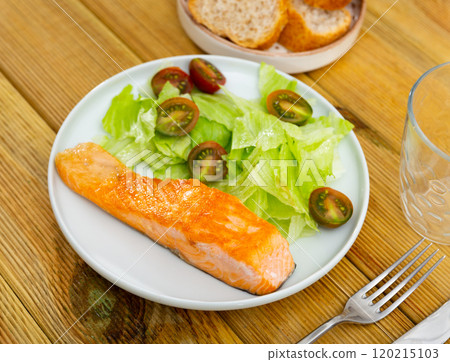 Tasty fried piece of salmon served on plate with salad Tasty fried piece of salmon served on plate with salad 120215103