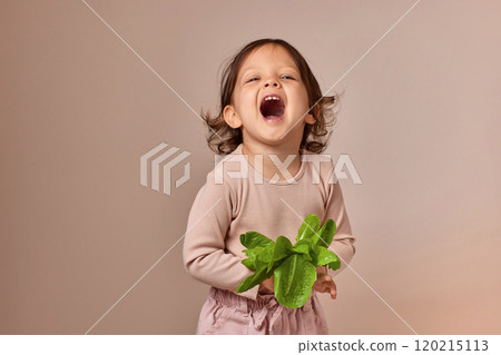 smiling child girl holding fresh green salad on beige background. healthy baby food. 120215113