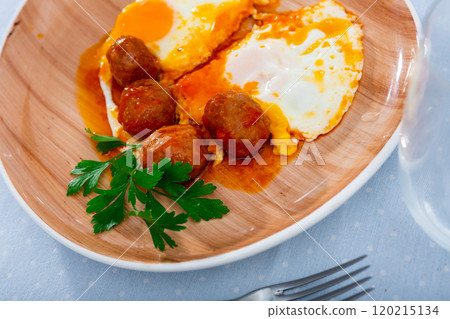 Fried eggs served with meatballs on plate 120215134