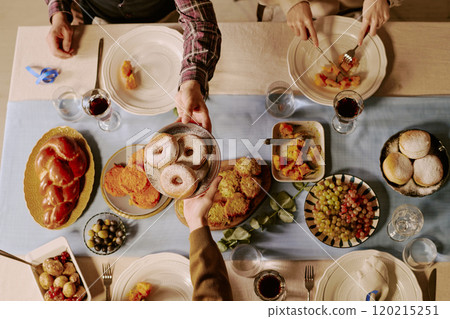 Top down shot of unrecognizable peoples hands holding round plate with fresh baked donuts covered with powdered sugar 120215251