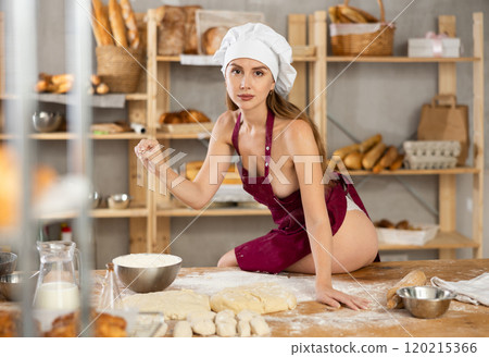 Woman in apron sitting on table in bakery 120215366