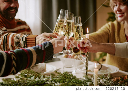 Medium close up of friends sitting at festive table and clinking glasses full of sweet champagne while spending X-mas eve together Medium close up of friends sitting at festive table and clinking glasses full of sweet champagne while spending X-mas eve together 120215410