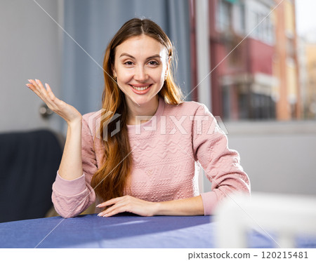 Portrait of a positive and confident young woman sitting at a table Portrait of a positive and confident young woman sitting at a table 120215481