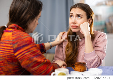 Woman complains to her friend about life while sitting at table with cups of tea Woman complains to her friend about life while sitting at table with cups of tea 120215495