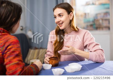 Two female friends drinking tea and talking at home Two female friends drinking tea and talking at home 120215496