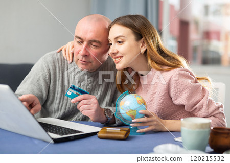 Happy married couple book a vacation tour on a laptop Happy married couple book a vacation tour on a laptop 120215532
