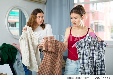 Sad young woman choosing clothes to wear 120215535
