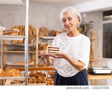 Woman chooses fresh sweet cake for breakfast in bakery 120215585