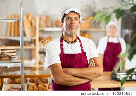 European man and woman sellers in white chefs hat stands in trading hall of bakery 120215625