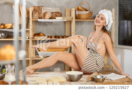 Woman in apron sitting on table in bakery 120215627